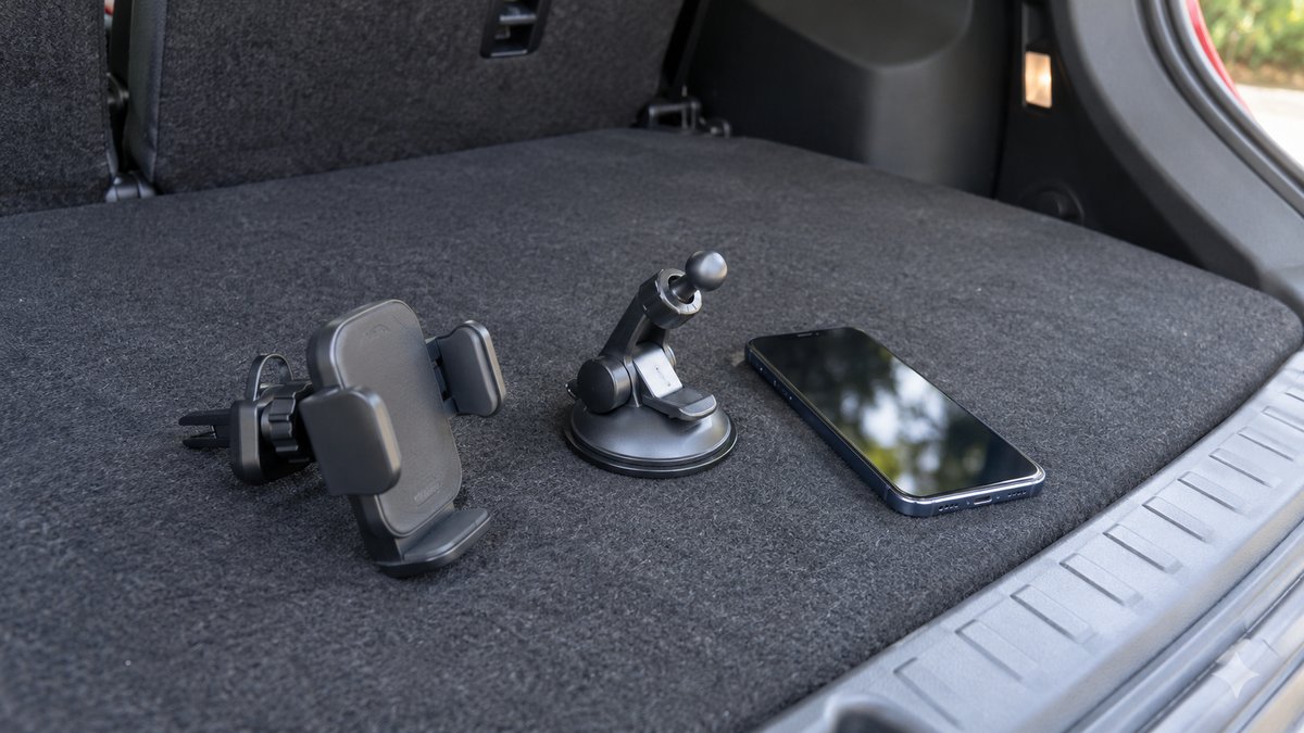 Two phone holder styles and a phone arranged on a car boot floor