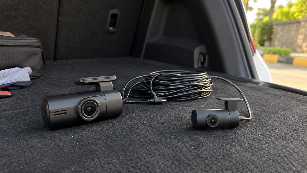 Front and rear dash cameras with a connecting cable on boot carpet